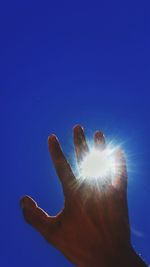 Low angle view of hand against clear blue sky