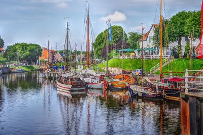 Boats moored at harbor against sky in city