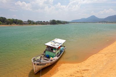 Boat moored on shore against sky