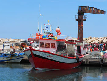 Boats moored at harbor against clear blue sky