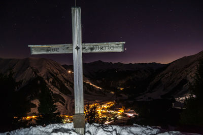 Summit cross on almkopf and valley of berwang by night