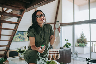 Smiling woman drinking milk in kitchen at home