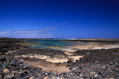 Scenic view of beach against blue sky