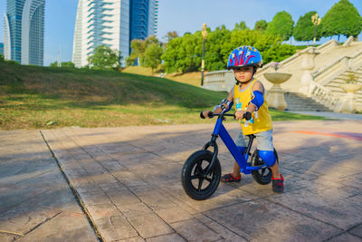 Portrait of cute boy riding bicycle on footpath at park