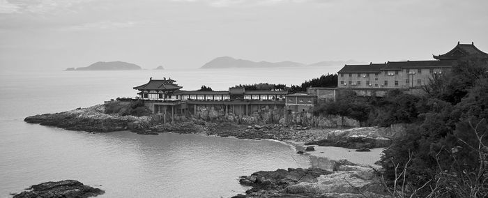 Built structure on river by buildings against sky