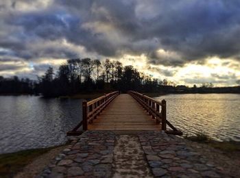 Pier over lake against sky during sunset