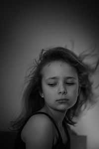 Portrait of young woman looking away against wall