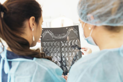 Rear view of female dentists examining x-ray at clinic