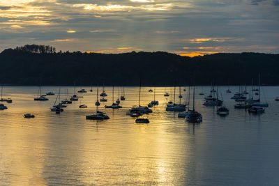 Sailboats in sea at sunset