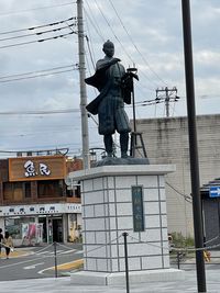 Statue on city against sky