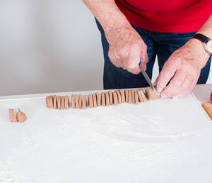 Midsection of man cutting cookies on table