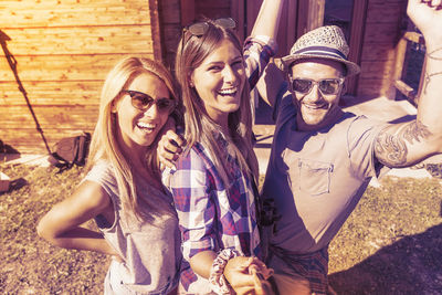 Group of smiling friends taking funny selfie with smart phone on a vintage warm color filtered look