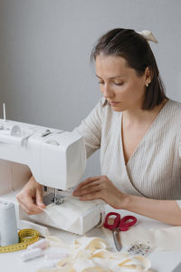 Young woman using sewing machine at home