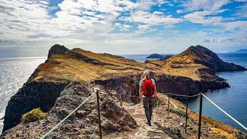 Rear view of woman standing on mountain against sky