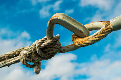 Close-up of rope tied on metal against sky