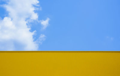 Low angle view of yellow wall against blue sky