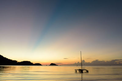 Silhouette sailboats moored on sea against sky during sunset