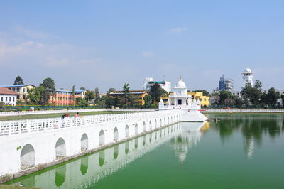 Bridge over river by buildings against sky