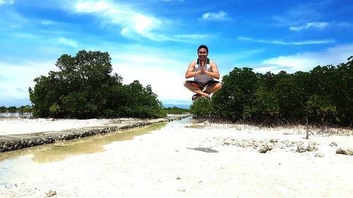 Young woman jumping in park against sky