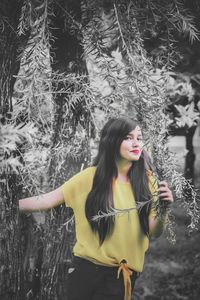 Young woman standing against trees