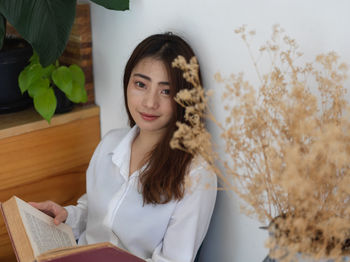 Young woman reading book while sitting at home