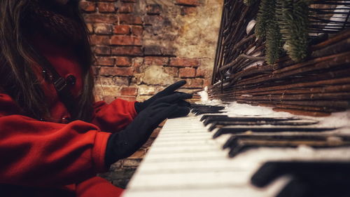 Midsection of woman playing abandoned piano during winter