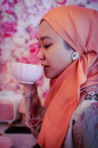 Portrait of woman drinking water on red rose