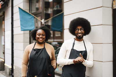 Portrait of smiling male and female coworkers standing outside barber shop