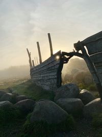 Stone wall by rocks against sky during sunset