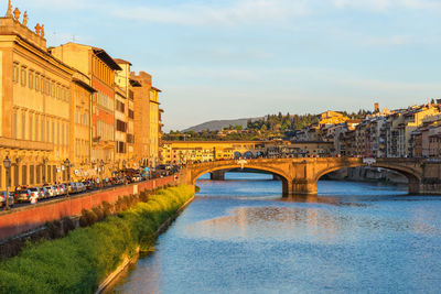 Arch bridge over river against buildings in city