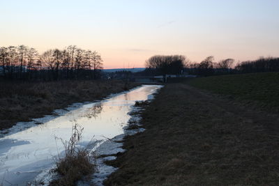 Scenic view of frozen river against sky during winter