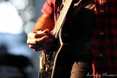 Midsection of man playing guitar