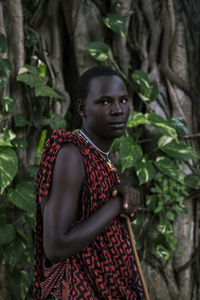 Maasai man in traditional clothes standing in the forest