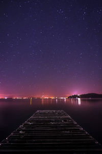 Scenic view of lake against clear sky at night with city lights in the background