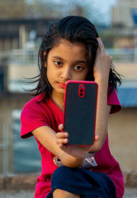 Cute little indian girl dressed casually clicking selfie with smartphone.