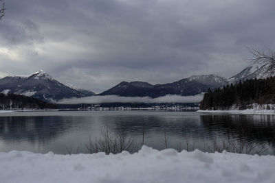 Scenic view of lake by snowcapped mountains against sky