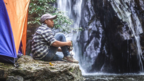 Rear view of man sitting on rock