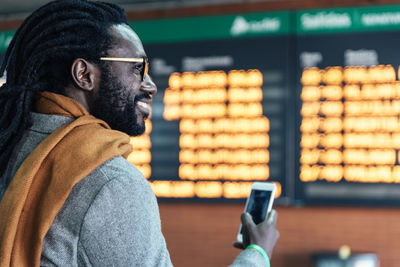 Smiling man using mobile phone at airport