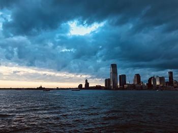 Sea by buildings against sky during sunset