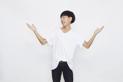 Portrait of young woman standing against white background