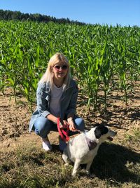 Portrait of woman with dog crouching on field