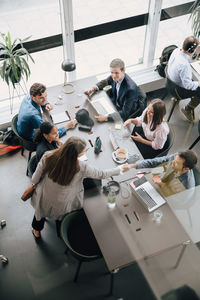 High angle view of team looking at professionals shaking hands in creative coworking space