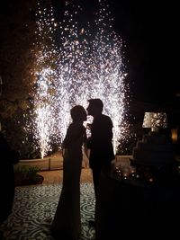 Silhouette couple kissing with fireworks in background