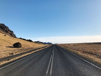 Road passing through landscape against clear sky