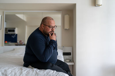 Side view of young man using mobile phone at home