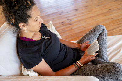 Woman reading with a kindle while relaxing in a wooden dome tent.