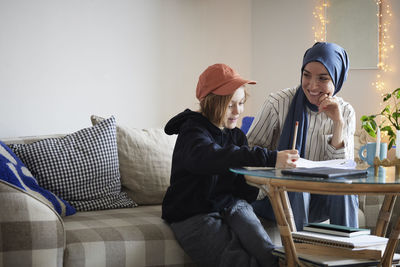 Mother wearing hijab helping son doing homework