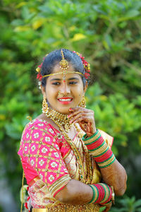 Young bride looking away while standing against plants