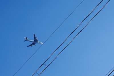 Low angle view of electricity pylon against blue sky