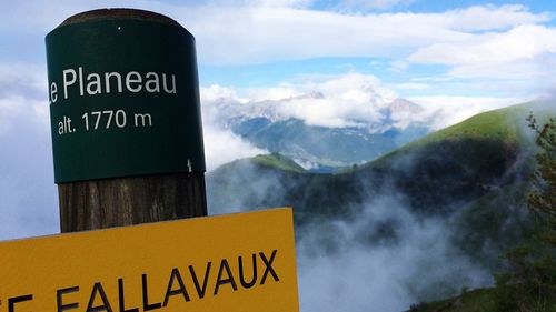 Low angle view of road sign against cloudy sky